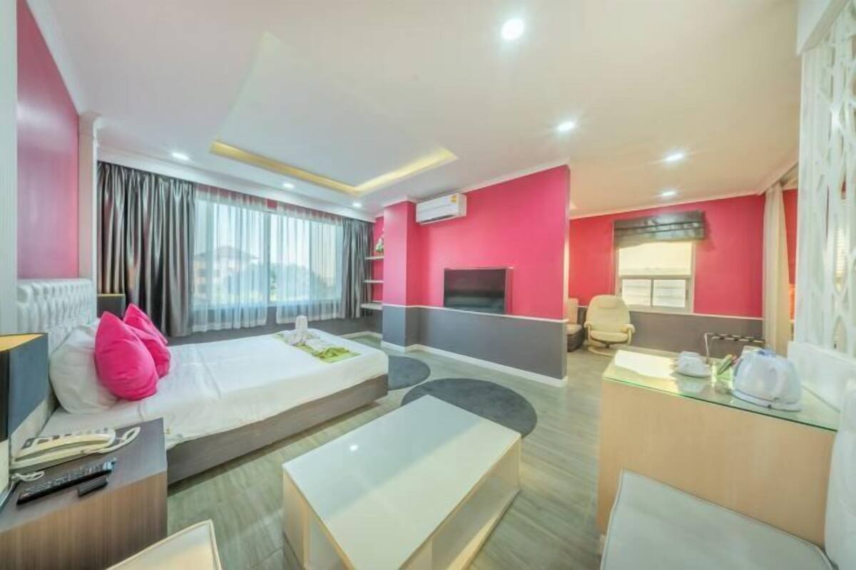 A hotel room with a bed, a desk, a chair, a TV, and a window with curtains.
