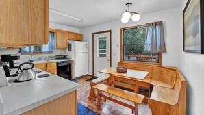 Une cuisine compacte avec des meubles en bois, une cuisinière encastrée et un coin repas équipé d’une banquette.