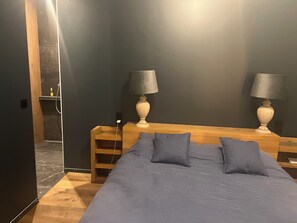Ein Schlafzimmer mit einem Bett, zwei Nachttischen, einem hölzernen Kopfteil und zwei Lampen.