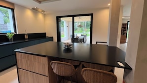 A modern kitchen with a large island, two wicker chairs, and a view of the outdoor patio. - ARCHITECT HOUSE SOUTH FACING 2 min FROM THE LANSERIA BEACH QUIMIAC MESQUER (Mesquer)