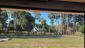 A view from a room with a wooden floor to a garden with a house and tall trees. - ARCHITECT HOUSE SOUTH FACING 2 min FROM THE LANSERIA BEACH QUIMIAC MESQUER (Mesquer)