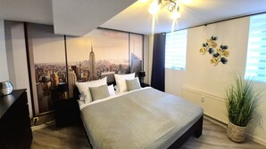 Un dormitorio moderno con una cama grande, un mural de paisaje urbano, un colgador de techo y una planta en maceta.