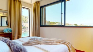 A hotel room with a bed, a window with a view of the sea, a mirror, and a flower on the nightstand. - Villa Flora Mare IV with Two Pools (Primošten)