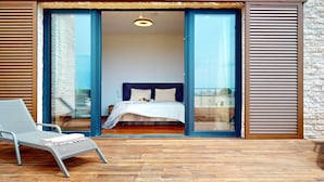Un dormitorio con cama, una silla y vistas a través de un ventanal.