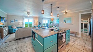 A spacious kitchen with a central island, a dining area with a view, and a living room with a sofa and TV. - Gulf Views + Pools, Tennis, Pickleball & Beach Access Awesome Beachfront by Avantstay (Port Aransas)