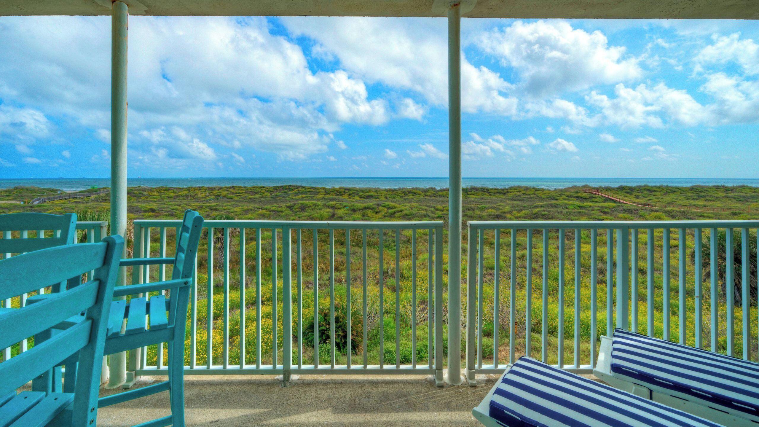 Varanda com vista para o oceano e vegetação costeira.