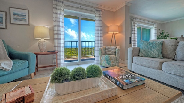A living room with a sofa, armchair, coffee table, and a book titled 'Ocean.' - Gulf Views + Pools, Tennis, Pickleball & Beach Access Awesome Beachfront by Avantstay (Port Aransas)