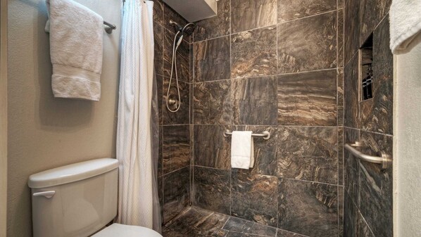 Ein Badezimmer mit Toilette, einer Duschkabine mit Glastür und einem Handtuchhalter.