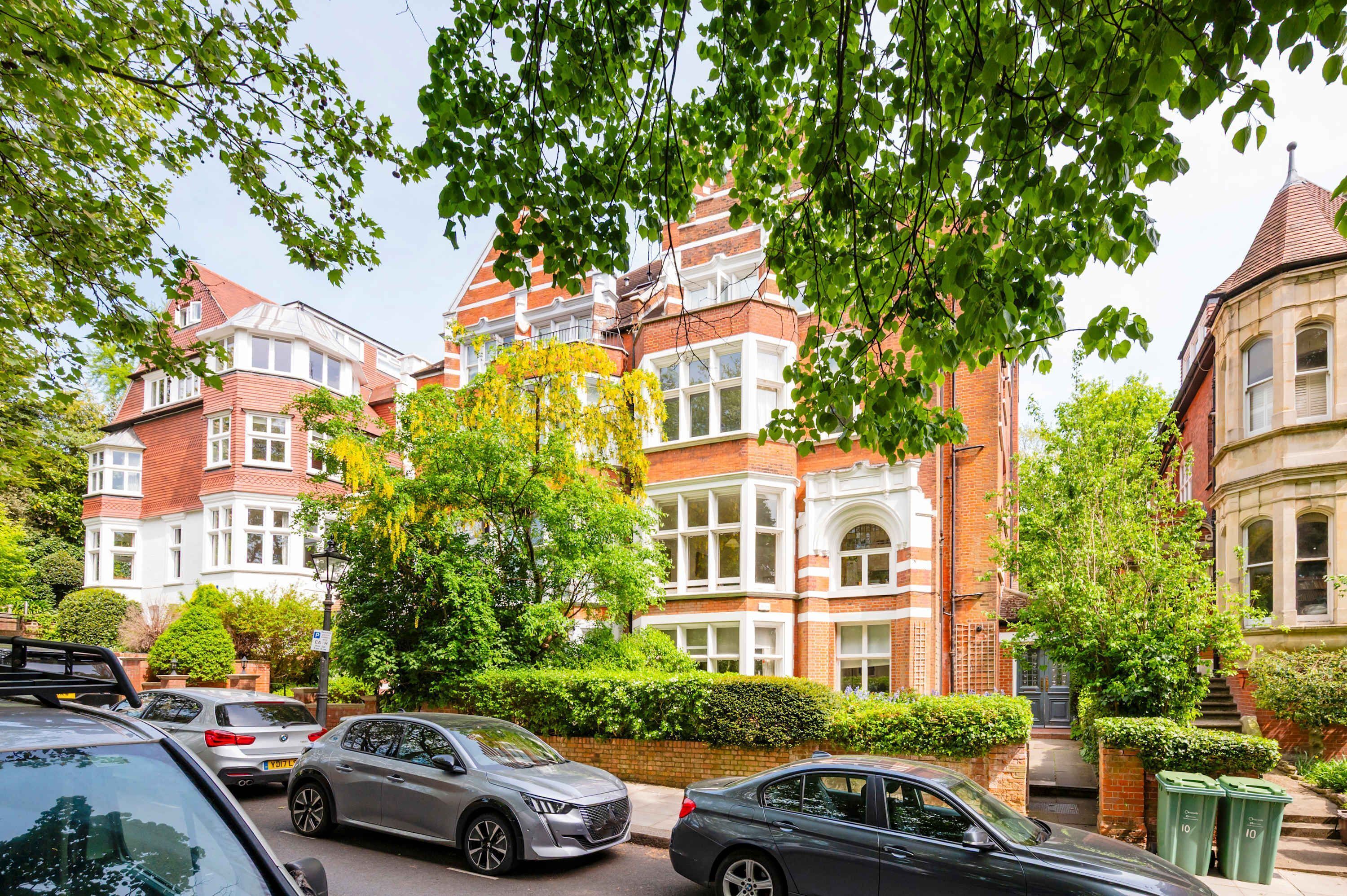 A row of red brick houses with white window frames and a tree in the foreground.