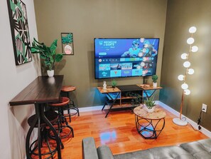 Una sala de estar moderna con televisor de pantalla plana, muebles de madera y plantas decorativas.