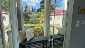 Ein Balkon mit einer Bank und Kissen, große Schiebeglasfenster und Blick auf eine Wohngegend.