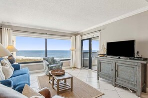 Een woonkamer met uitzicht op de oceaan, een televisie en een kast.