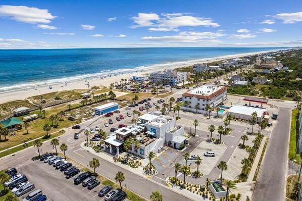 Vista aérea de una zona costera con playa, estacionamientos y edificios.