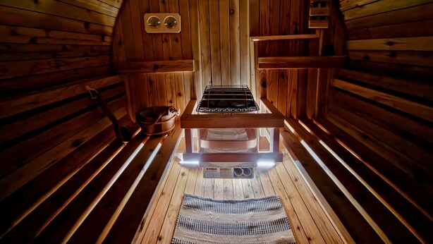 Una sauna con paredes de madera, un banco, un asiento y un perchero, además de un espejo.