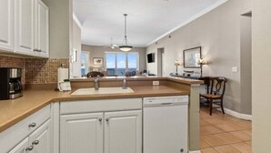 A kitchen with white cabinets, a dishwasher, a coffee maker, and a tiled backsplash.