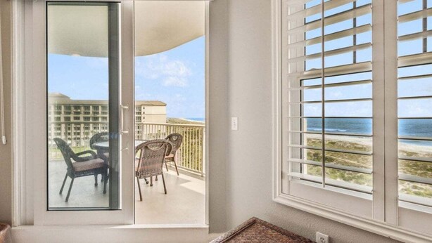 A room with a sliding glass door leading to a balcony with outdoor furniture.