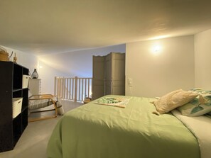 Ein Schlafzimmer mit einem Bett, einem Kleiderschrank, einem Schreibtisch und einem Sessel.