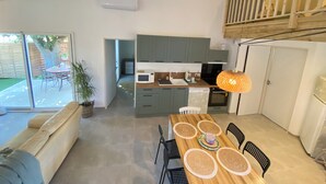 A modern kitchen with grey cabinets, a wooden dining table with placemats, and a hanging pendant light. - L'An'Phi- Charming house with outdoor spa (Vaison-la-Romaine)