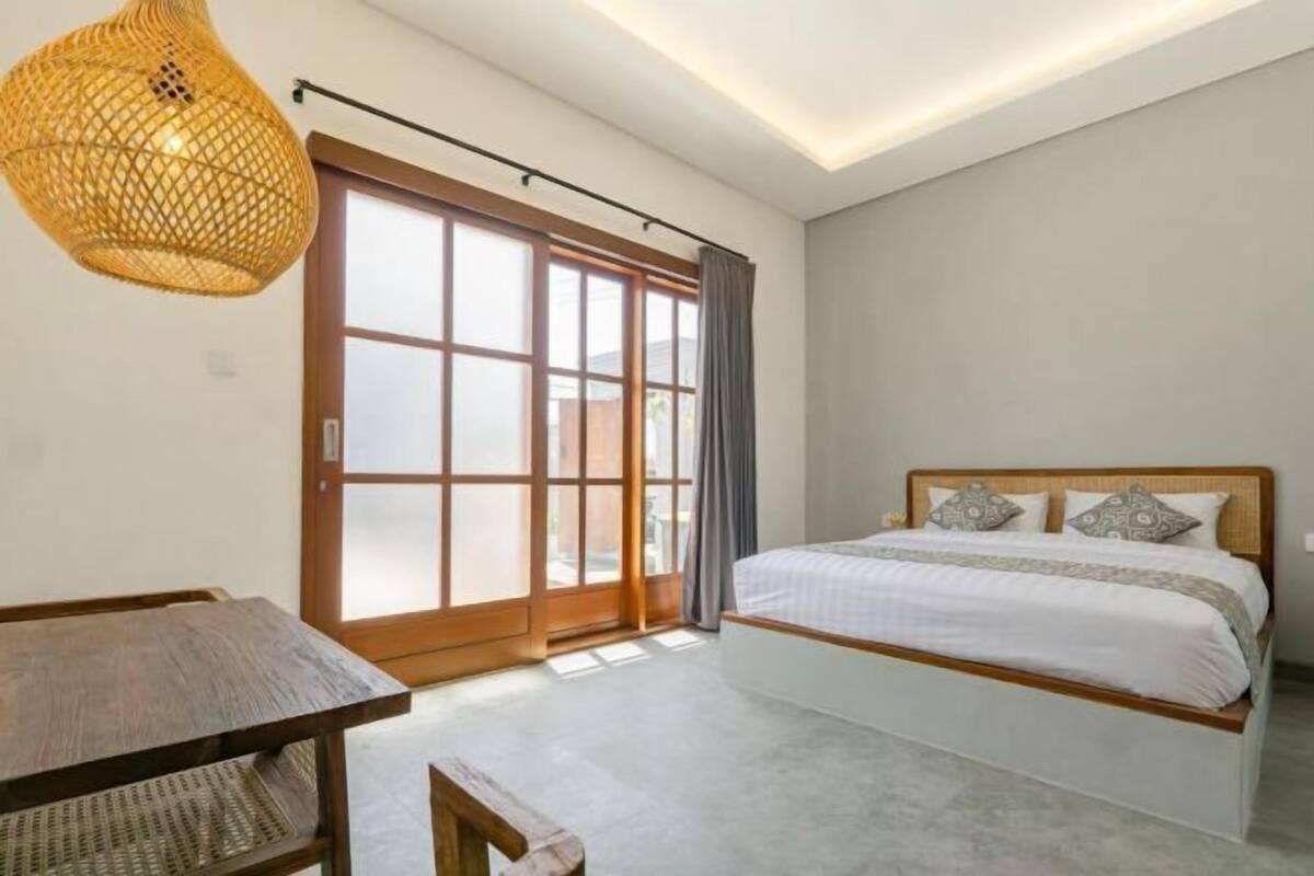Une chambre à coucher avec un lit, une table et une grande fenêtre avec des rideaux.