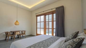 A bedroom with a large bed, a desk, and a hanging light fixture.