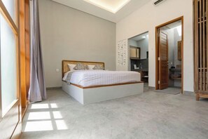 A bedroom with a large bed, a wardrobe, and a bathroom visible through an open door. - Kardi Residence By Bali Cabin (Bali)