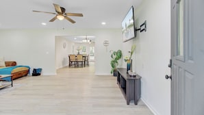 Un vaste espace de vie comprenant une table à manger, un canapé et un ventilateur de plafond.