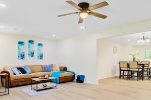 A modern living room with a sofa, coffee table, and a dining area with chairs.