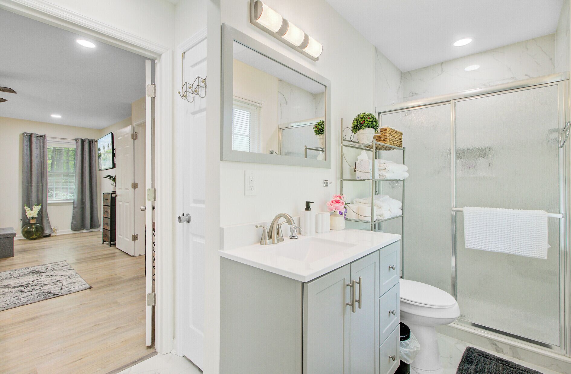 Un bagno moderno con cabina doccia in vetro, un lavandino bianco con specchio sopra e il water.