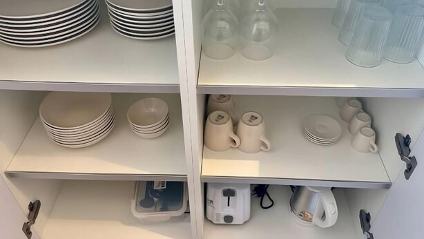A kitchen with white cabinets, a coffee maker, and various kitchenware including plates, cups, and wine glasses. - Villa La Balinaise - Vue Mer, Villa 16 (Koh Samui)