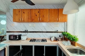 Een keuken met houten kastjes, een magnetron, een broodrooster, een gasfornuis en een spoelbak.