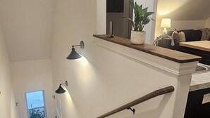 Een houten trap met een leuning, een plant in een pot en een raam met uitzicht.