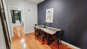 A dining area with a wooden table and chairs, a potted plant, and a wall-mounted picture. - Prime / 2 King Beds / 65" TV / Jefferson Hospital (Philadelphia)