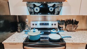 A kitchen with a stove, pots, and a knife block. - Prime / 2 King Beds / 65" TV / Jefferson Hospital (Philadelphia)