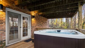 Ein Whirlpool unter einer Holzhütte mit einer Ziegelwand und Glastüren.