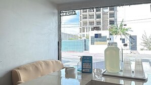 A hotel room with a bed, a desk with a laptop, a window with a view of buildings, and a vending machine. - Hotel VillaS INN (León)