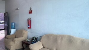 A living room with a sofa, a chair, a water dispenser, and a fire extinguisher. - Hotel VillaS INN (León)
