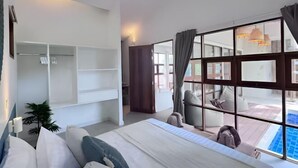 A modern hotel room with a large bed, a walk-in closet, a view of a pool, and a dining area with outdoor seating. - Villa Blue Paradise, Villa 22 (Koh Samui)