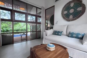 A modern living room with a white sofa, a wooden coffee table, and a large window. - Villa Blue Paradise, Villa 22 (Koh Samui)