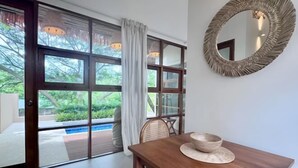 A dining area with a wooden table, a woven chair, and a decorative bowl. A large mirror with a textured frame hangs on the wall. - Villa Blue Paradise, Villa 22 (Koh Samui)