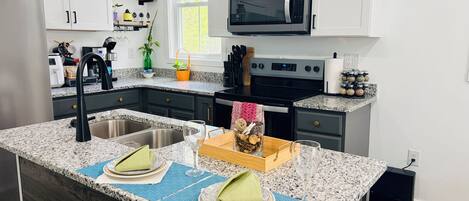 A modern kitchen with granite countertops, stainless steel appliances, and a central island with a sink.
