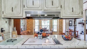 A kitchen with white cabinets, a stainless steel range hood, and a dining area with a wooden table and chairs. - Rural Retreat: ‘Cypress Lake’ By Roosevelt St Park (Morton)