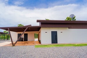 Et moderne hus med en overdækket terrasse, en parabolantenne og en velplejet græsplæne.