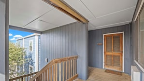 A wooden staircase leading to a porch with a view of neighboring houses. - Steps to Sand! 3rd-Floor North Topsail Beach Condo (North Topsail Beach)