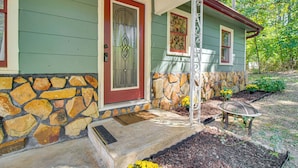 A house with a stone foundation, a red door, and a small porch with a bench. - Mammoth Spring River Retreat: Family Gem, Big Yard (Mammoth Spring)