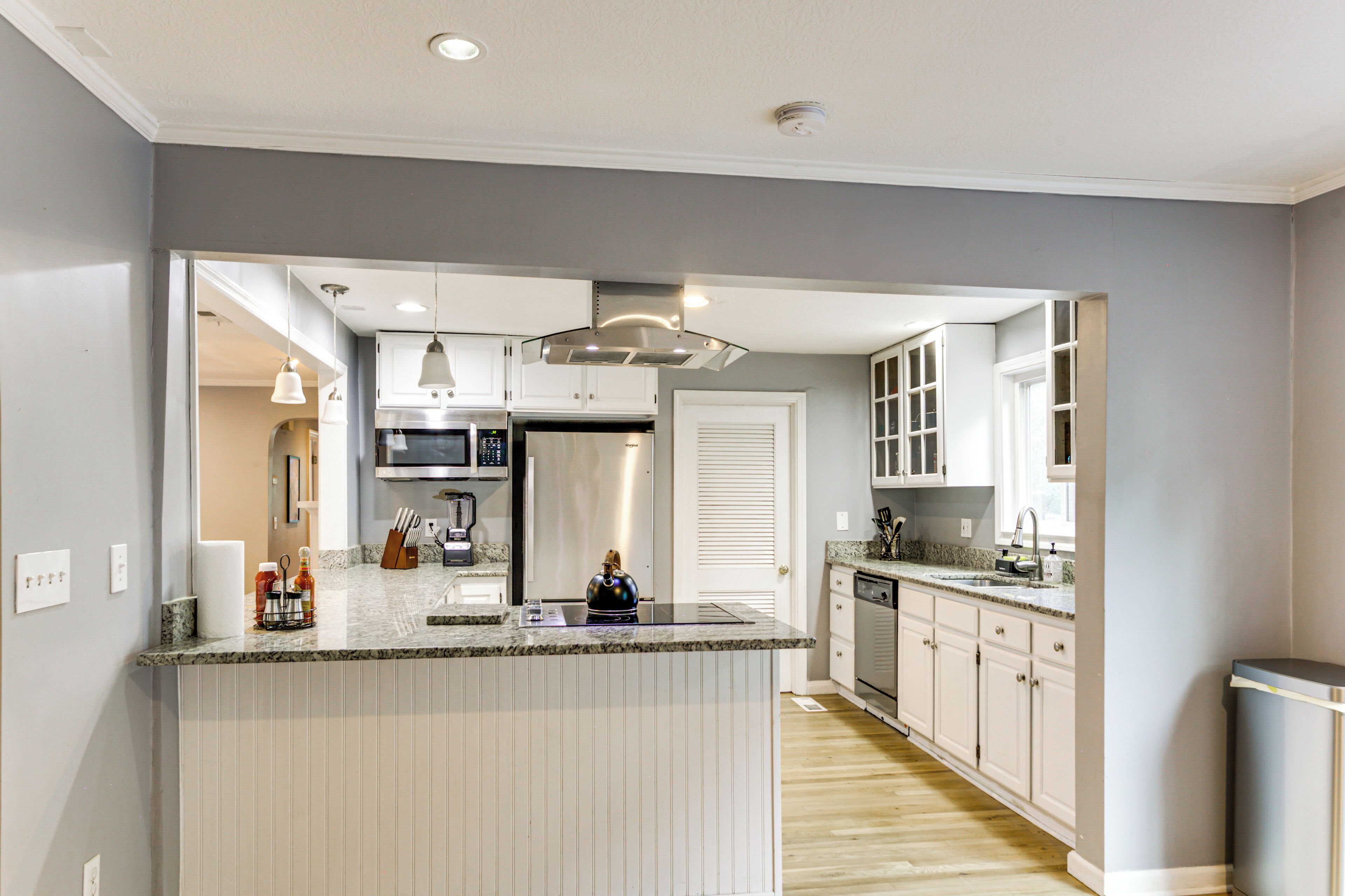 A modern kitchen with a central island, stainless steel appliances, and light-colored cabinetry.