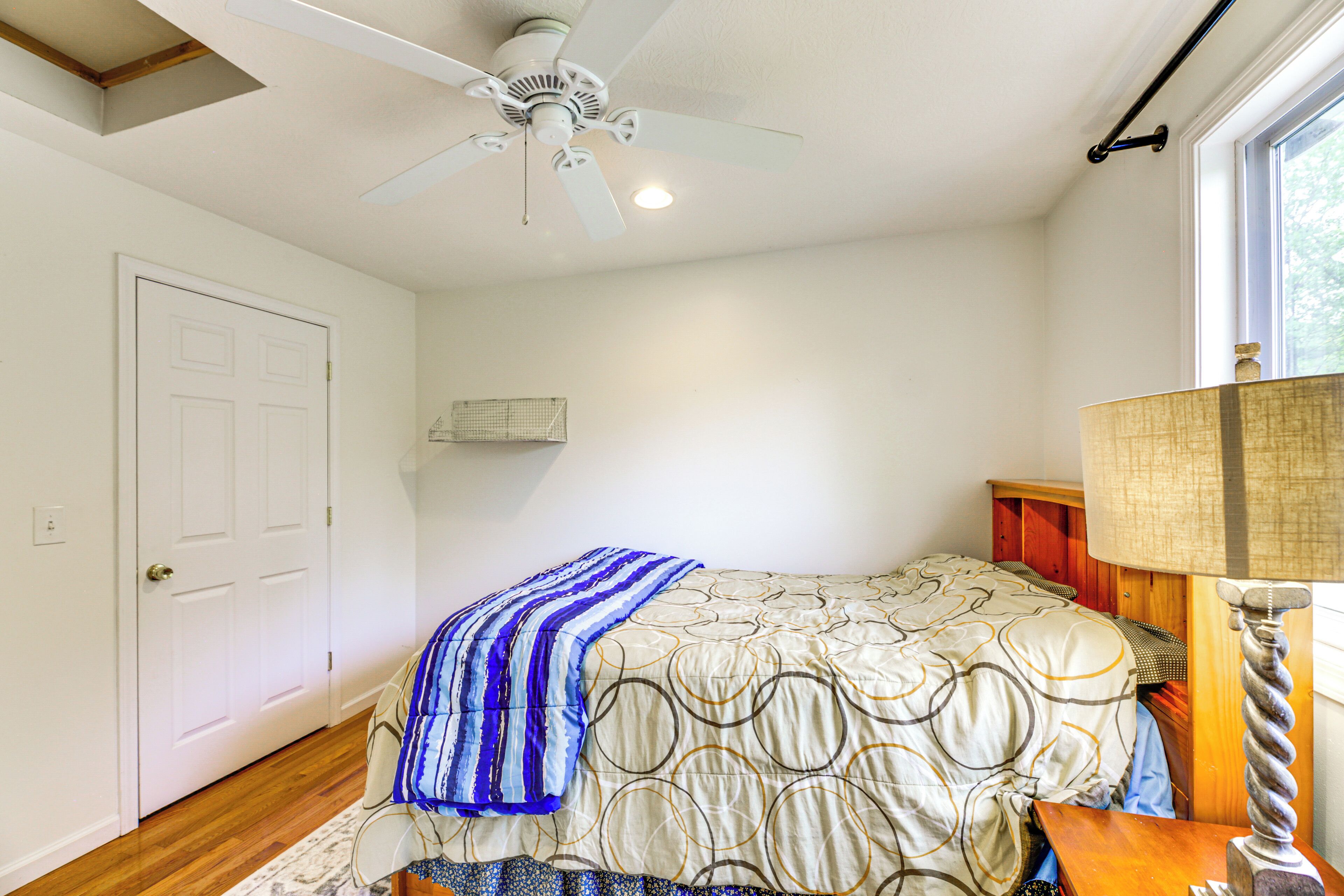 A bedroom with a bed, a ceiling fan, a window, and a door.