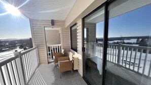 Un balcón con vistas a un paisaje nevado, muebles de mimbre y una puerta de cristal que da al interior.