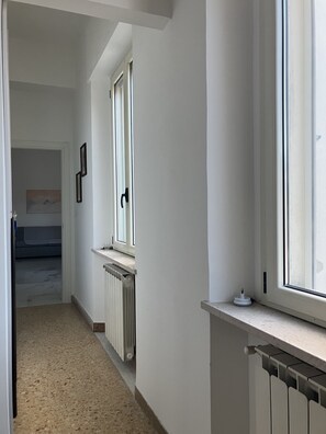 Un corridoio stretto con termosifone, una finestra e una porta che dà su un'altra stanza.