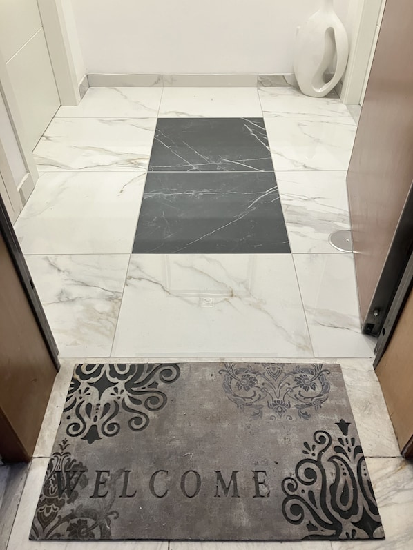 A tiled floor with a welcome mat at the entrance.