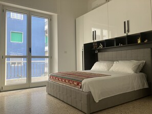 Een slaapkamer met een bed, een schuifglazen deur en een inbouwkast.